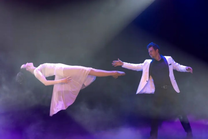 Magician levitating a woman on stage with fog and spotlight.