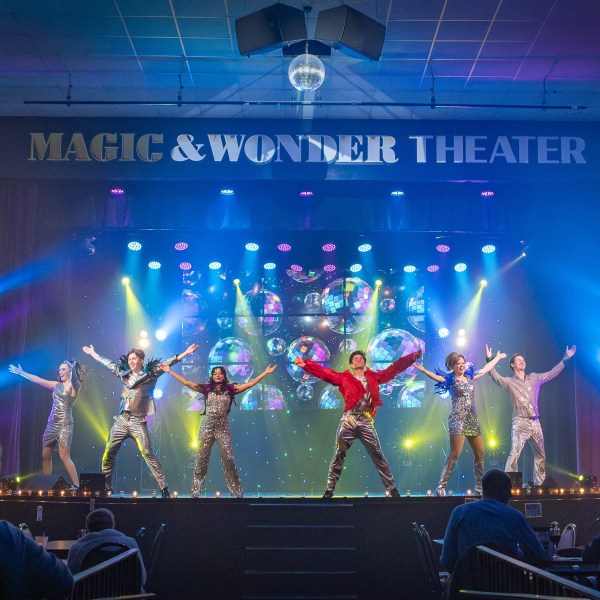 Performers dancing on stage with colorful lights at Magic & Wonder Theater.