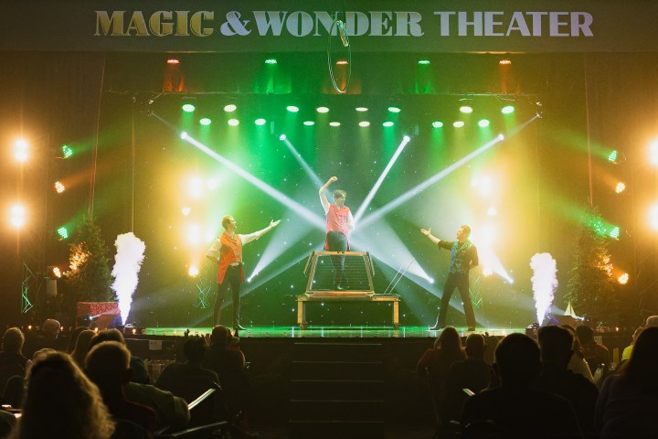 Three performers on stage with colorful lights at Magic & Wonder Theater.