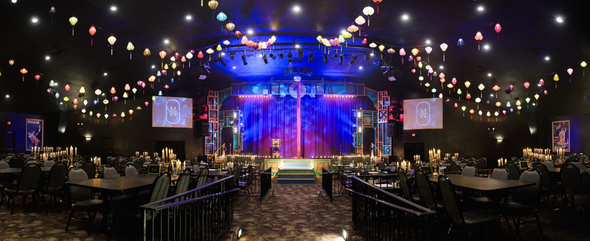 A decorated event hall with colorful hanging lanterns and a stage.