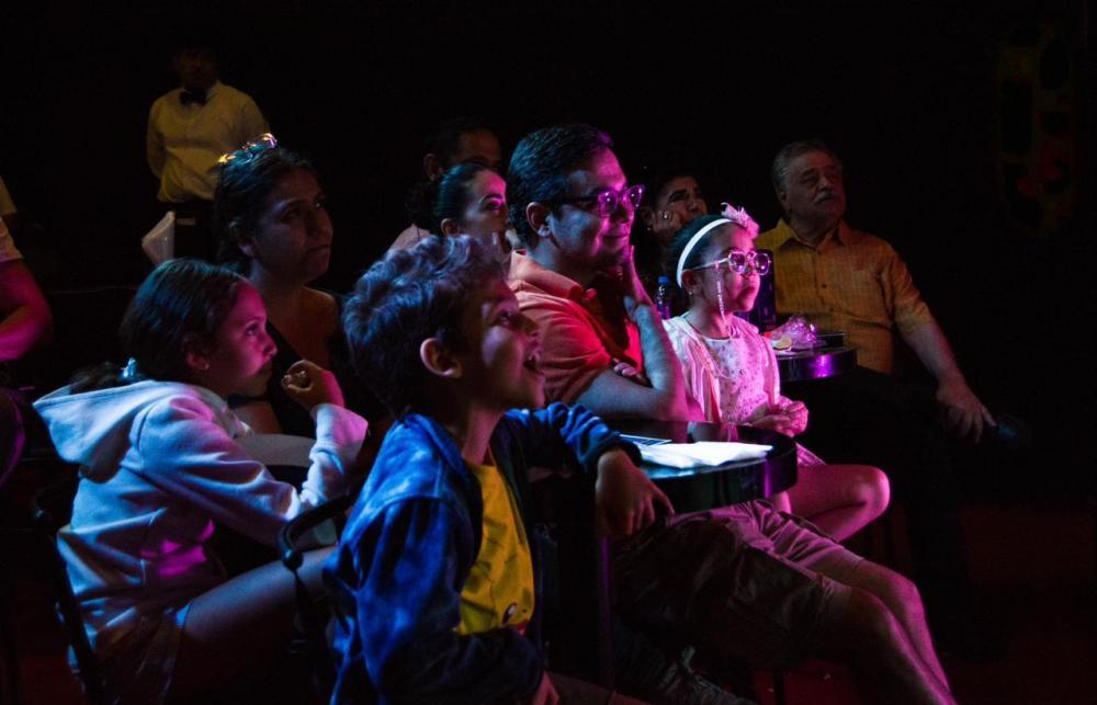 Rainy Day Activities in Lancaster, PA Audience in colorful lighting, seated and watching attentively.