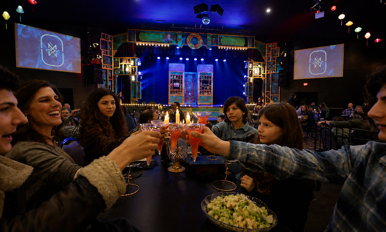 Group toasting with drinks at a vibrant stage show venue.