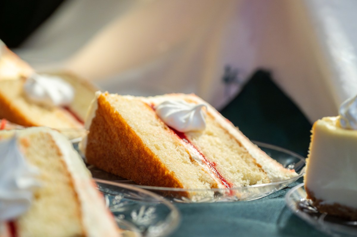 Slices of layered cake with cream and jam on plates.